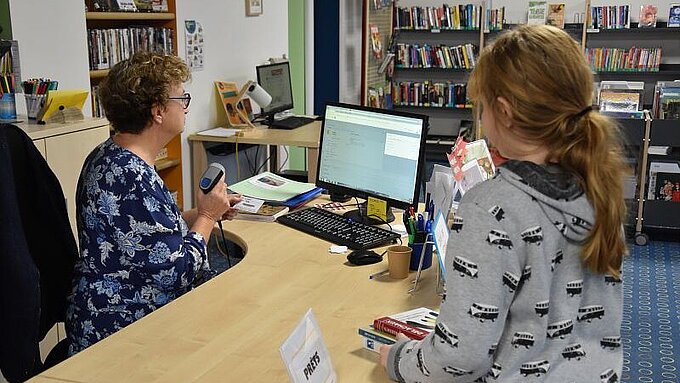 Enfant qui emprunte des livres à la bibliothèque de Couffé